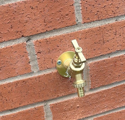 Brass outdoor garden tap fitted to a brick wall